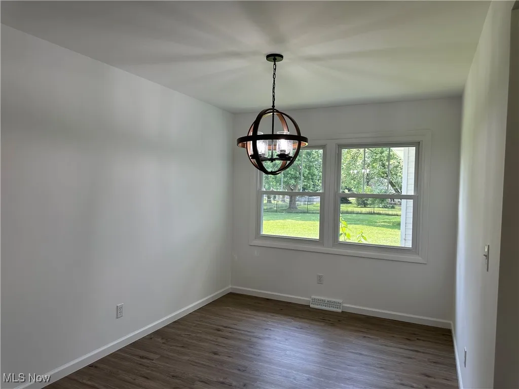 Empty room with a chandelier and dark wood finished floors