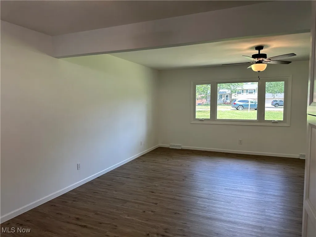 Unfurnished room featuring dark wood-style flooring and a ceiling fan