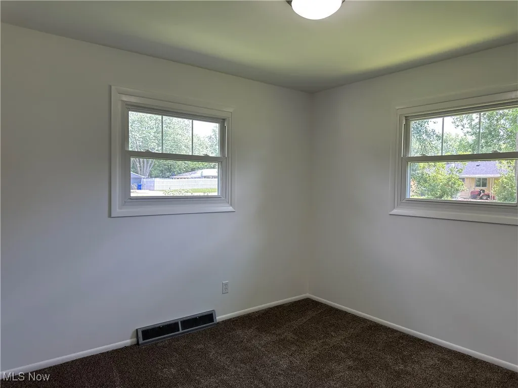 Spare room with dark carpet and baseboards