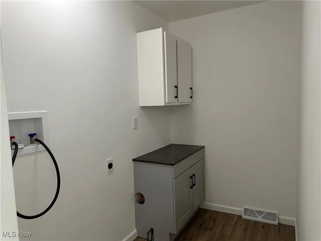 Laundry room with cabinet space, dark wood-style flooring, hookup for a washing machine, and electric dryer hookup