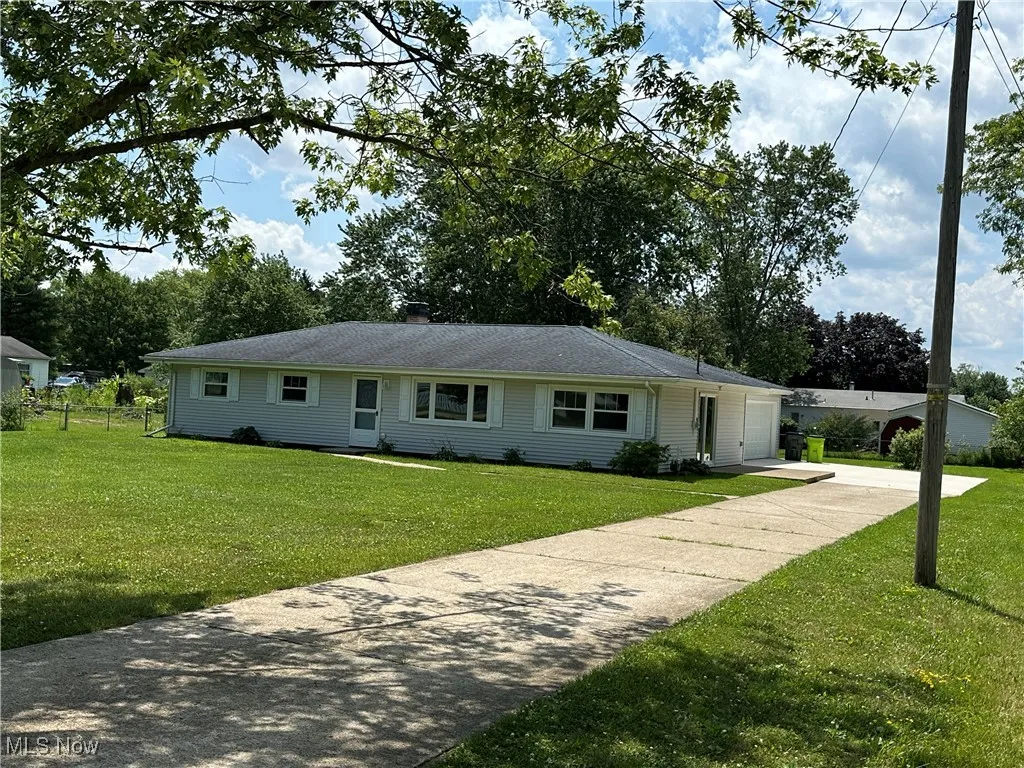 Ranch-style house featuring concrete driveway, a front lawn, and a chimney