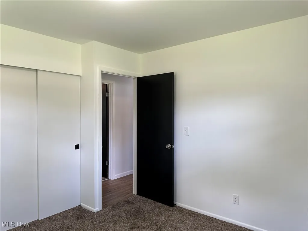 Unfurnished bedroom with dark carpet and a closet