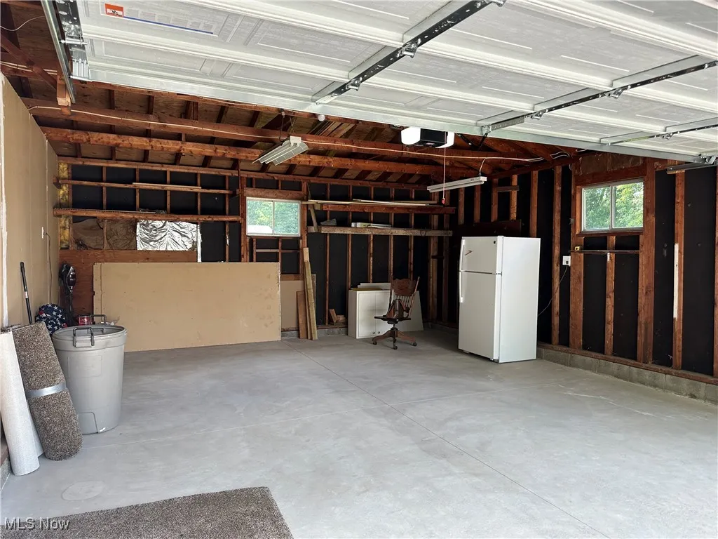Garage featuring freestanding refrigerator and a garage door opener