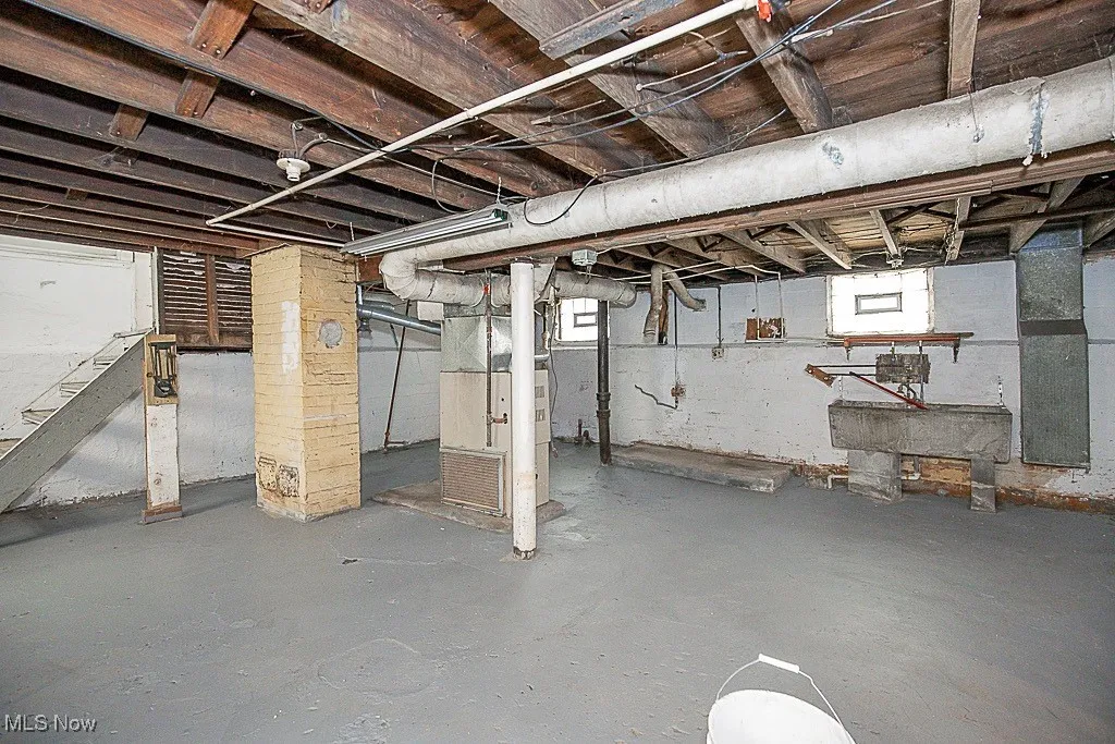 Basement featuring heating unit and stairway