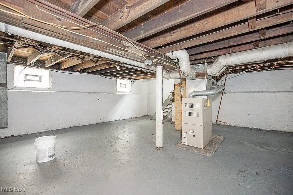 Below grade area featuring stairway and heating unit