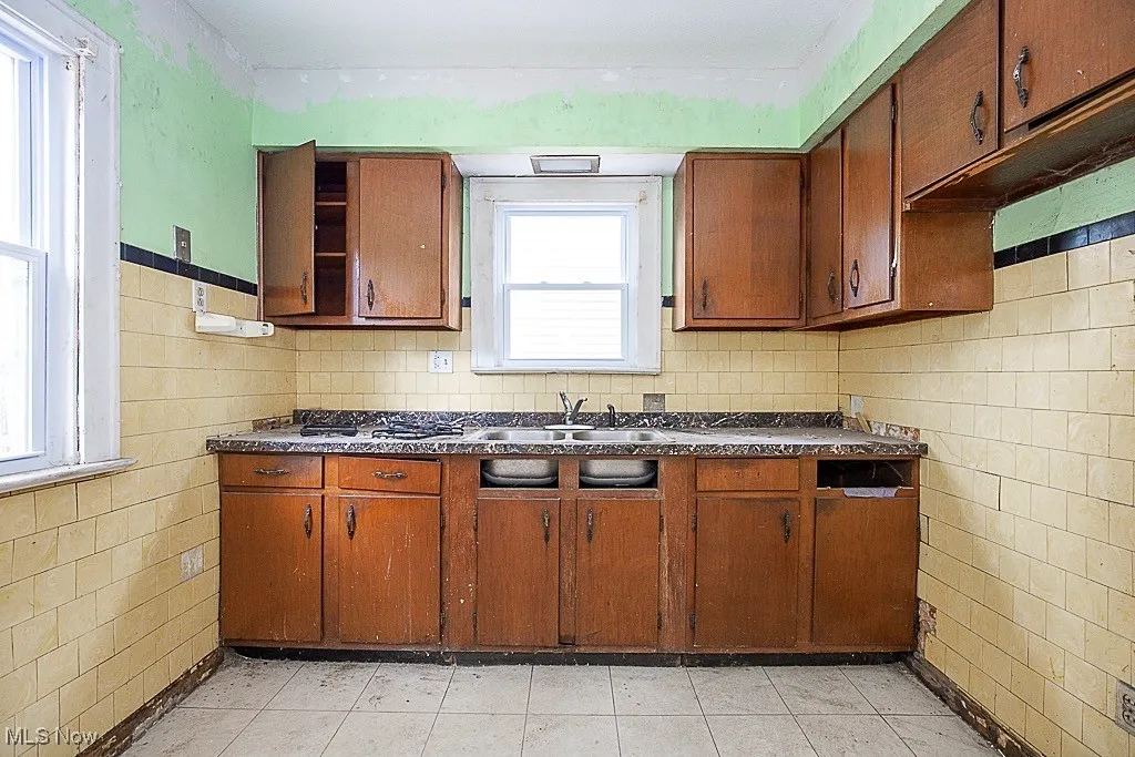 Kitchen with dark countertops, brown cabinetry, and tile walls