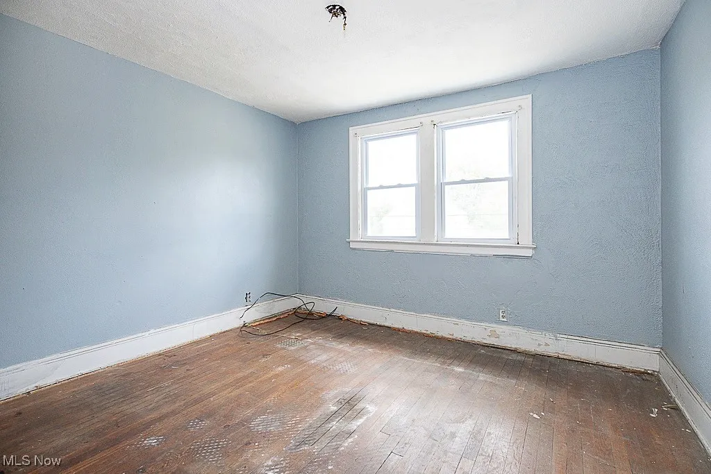 Unfurnished room featuring hardwood / wood-style floors and baseboards