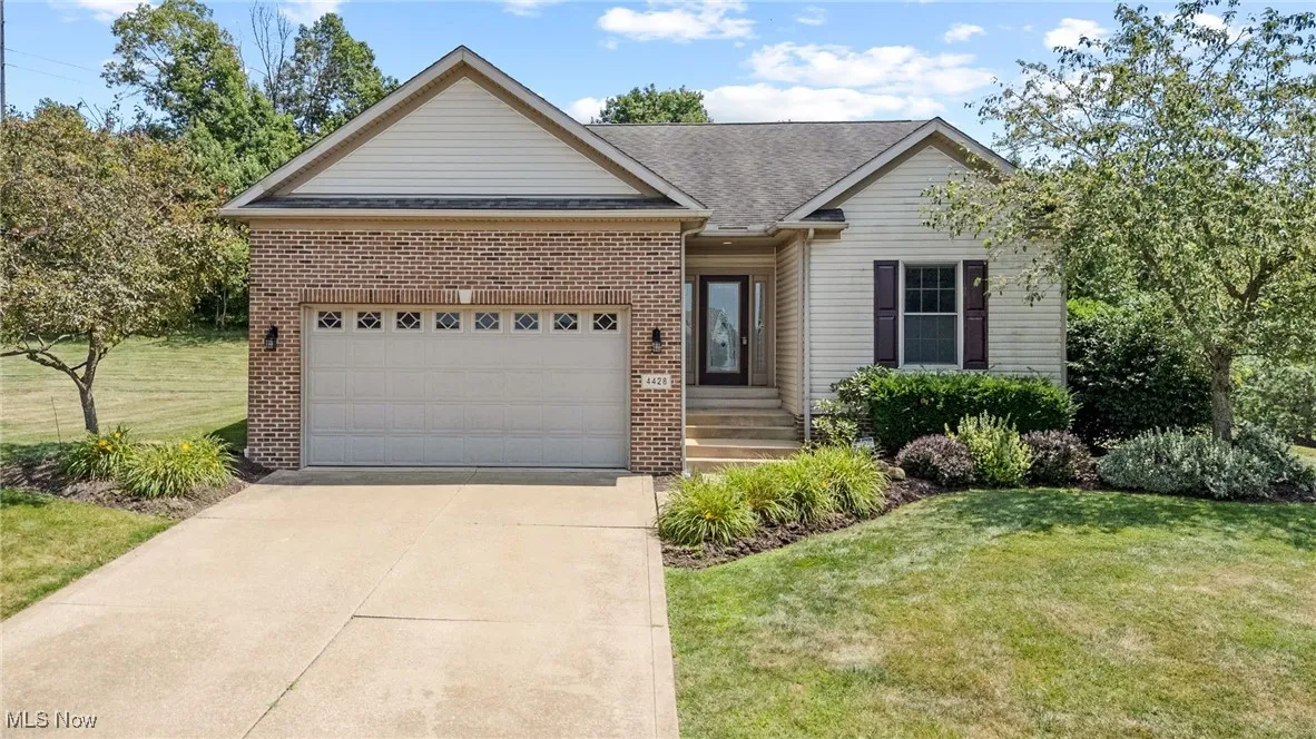 Single story home with brick siding, driveway, roof with shingles, an attached garage, and a front lawn