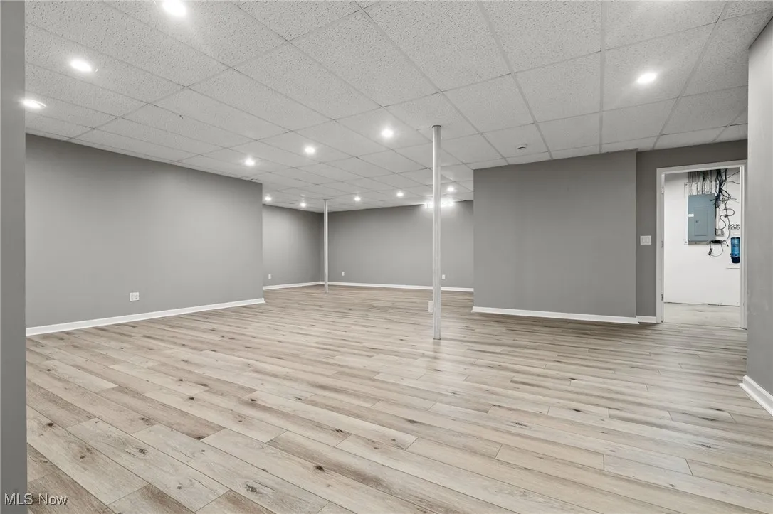 Finished below grade area featuring light wood finished floors, electric panel, and recessed lighting