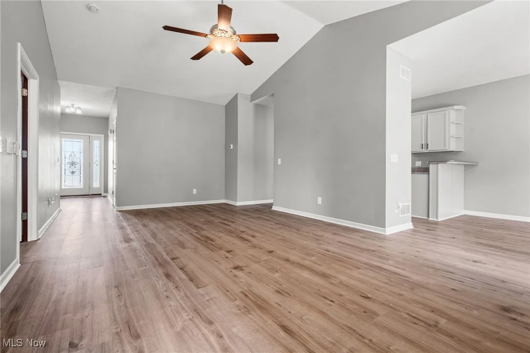 Unfurnished living room with ceiling fan, lofted ceiling, and light wood-type flooring