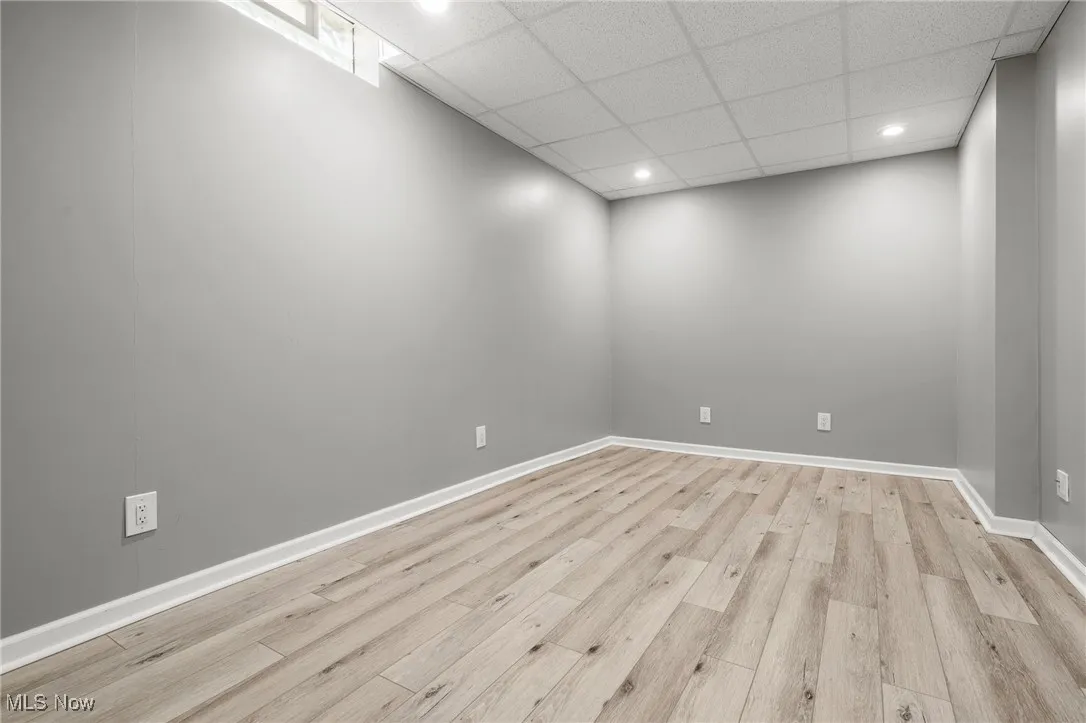 Spare room with light wood-style flooring, a drop ceiling, and recessed lighting