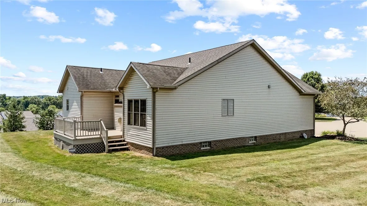 Back of property with roof with shingles, a yard, and a wooden deck