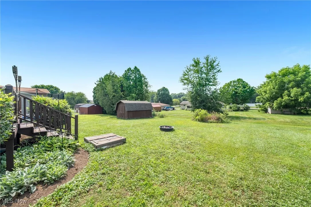 View of green lawn featuring a storage shed and a fire pit
