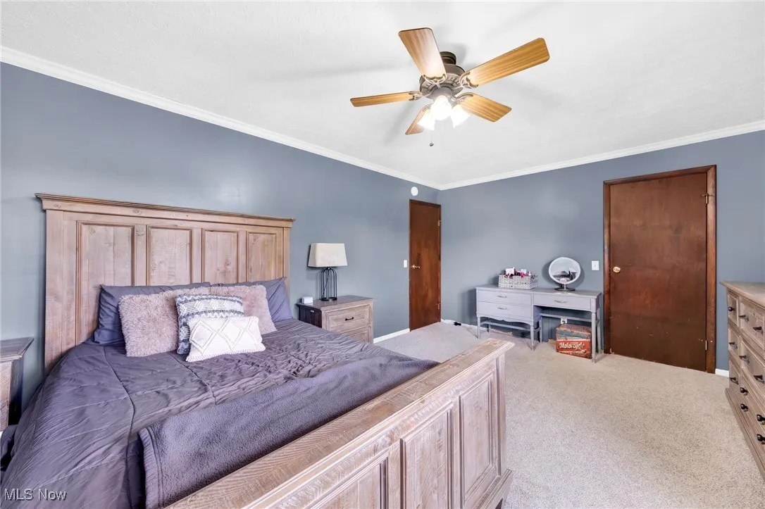 Carpeted bedroom featuring crown molding and a ceiling fan