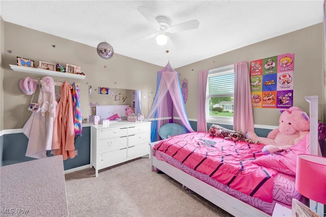 Bedroom with carpet floors, ceiling fan, and a textured ceiling