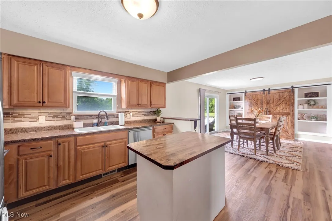Kitchen featuring dishwasher, wooden counters, wood finished floors, tasteful backsplash, and a textured ceiling