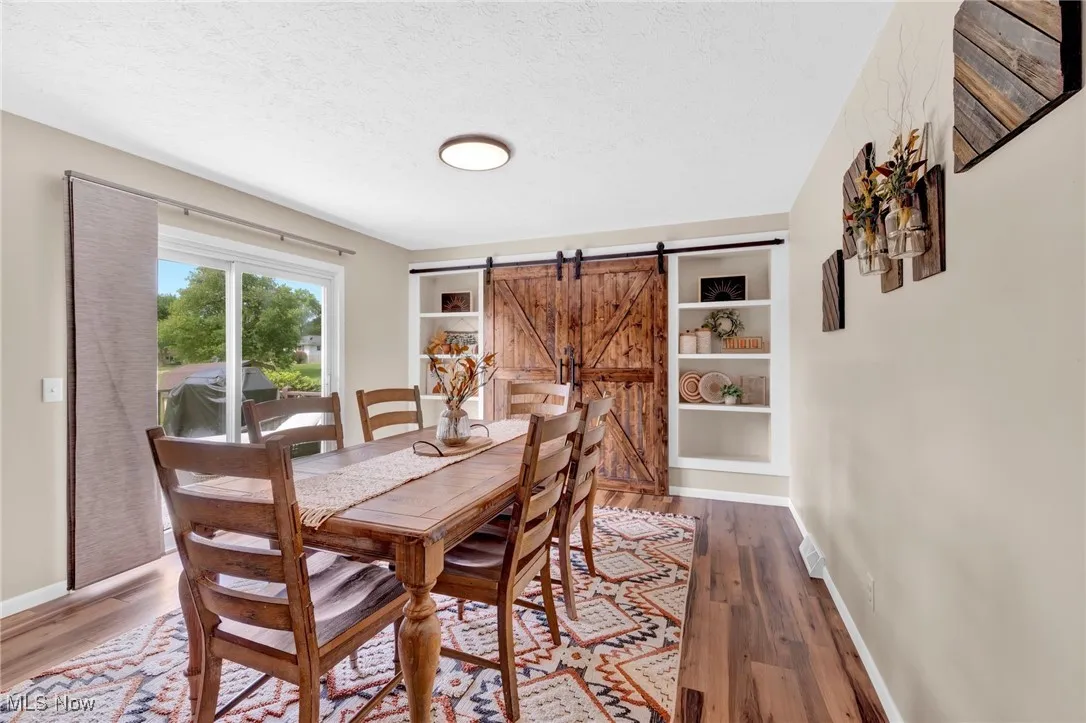 Dining room with a barn door, wood finished floors, and a textured ceiling