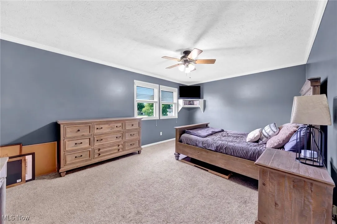 Bedroom featuring ornamental molding, carpet floors, a textured ceiling, and ceiling fan