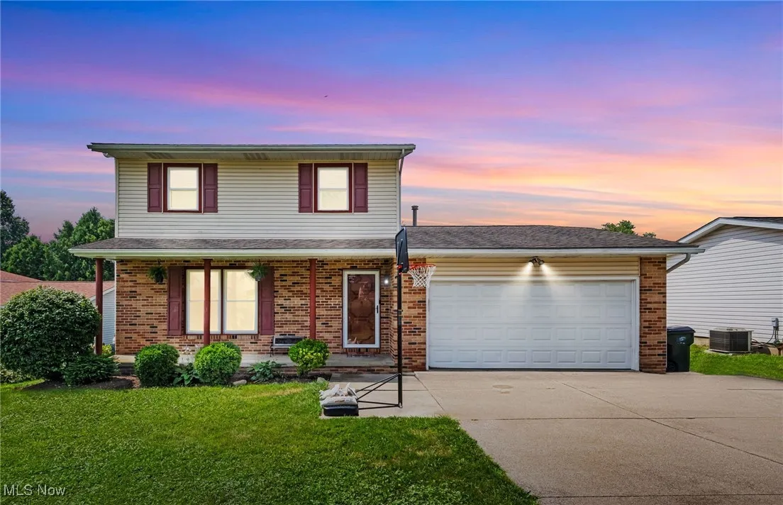 Traditional home featuring driveway, a garage, a yard, and brick siding