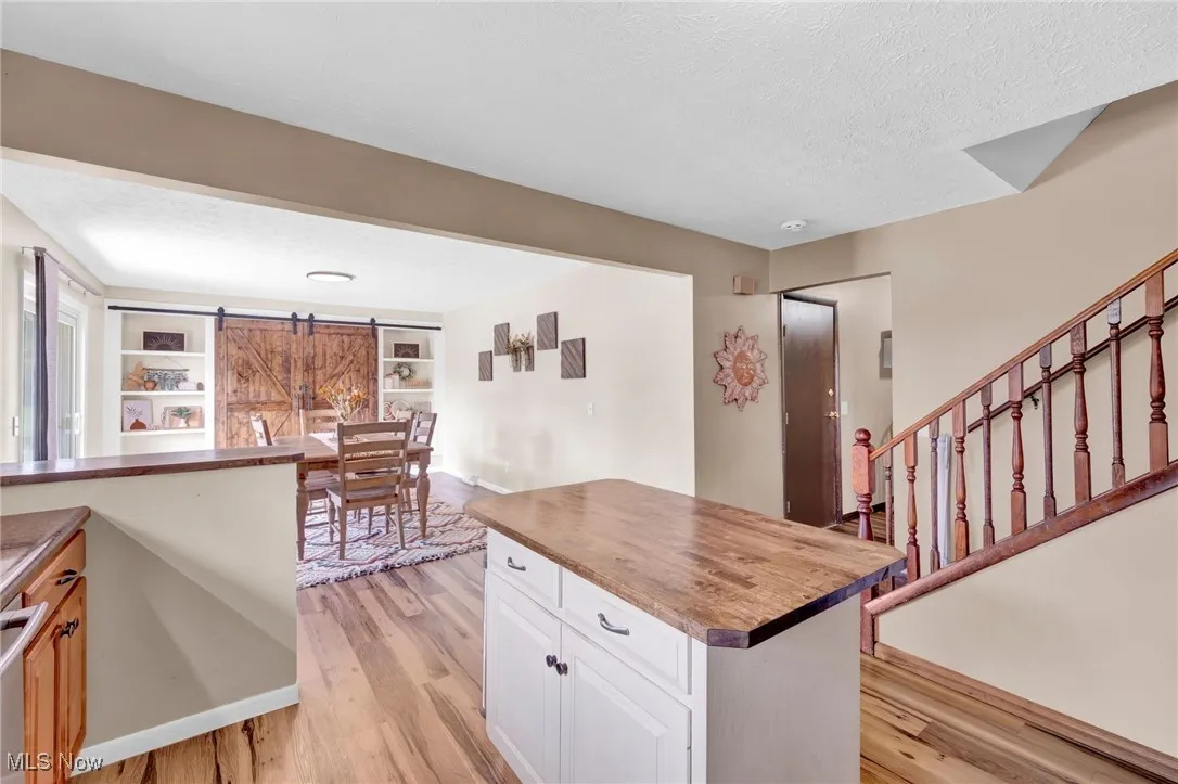 Kitchen with a barn door, light wood-style flooring, butcher block countertops, white cabinetry, and a textured ceiling