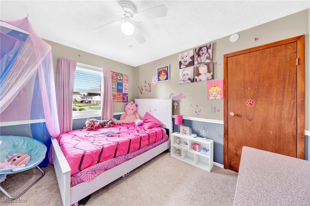 Carpeted bedroom featuring a ceiling fan and a textured ceiling