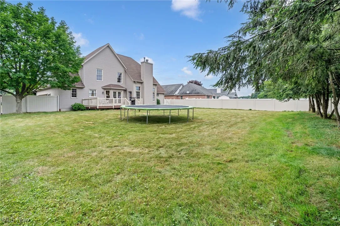 View of yard featuring a trampoline and a wooden deck