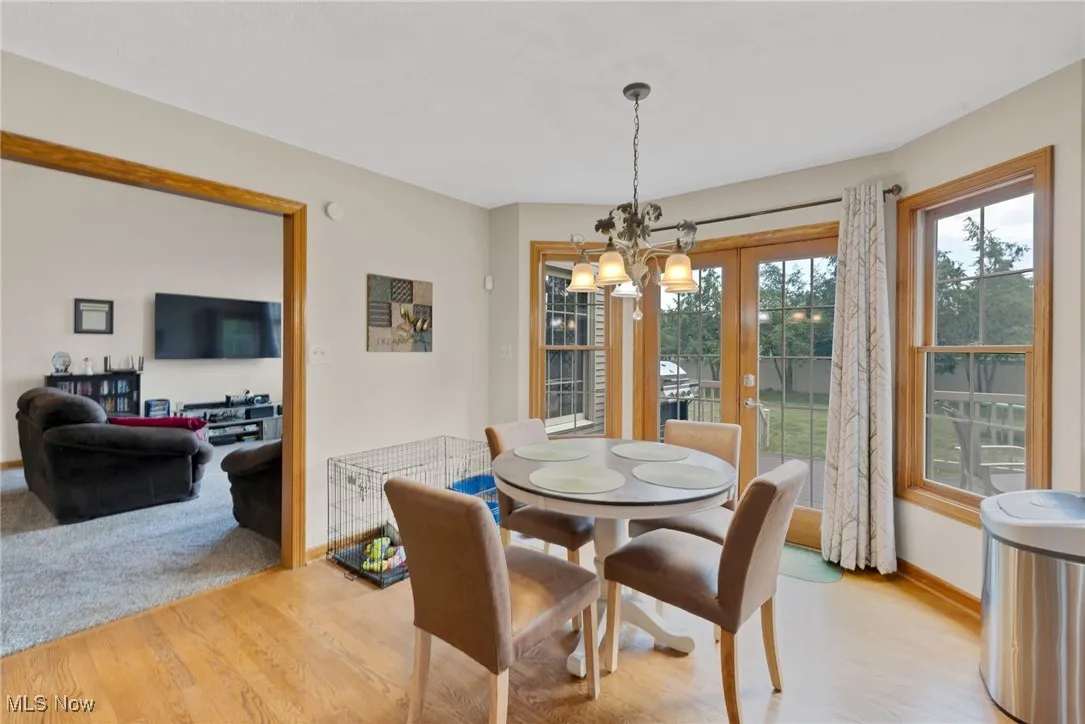Dining space featuring light wood-type flooring, a chandelier, and french doors