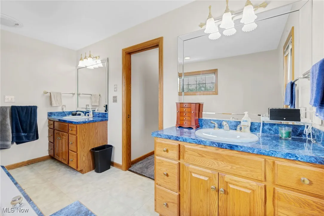 Full bath featuring two vanities and baseboards
