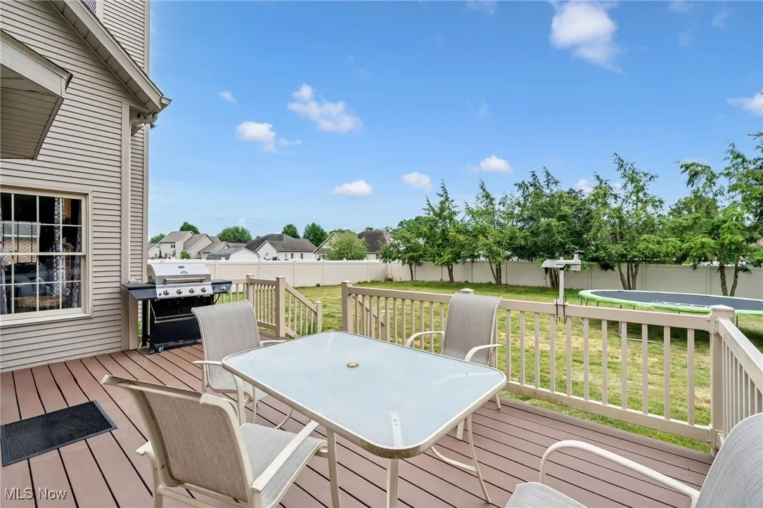 Wooden deck featuring grilling area, outdoor dining space, and a fenced backyard