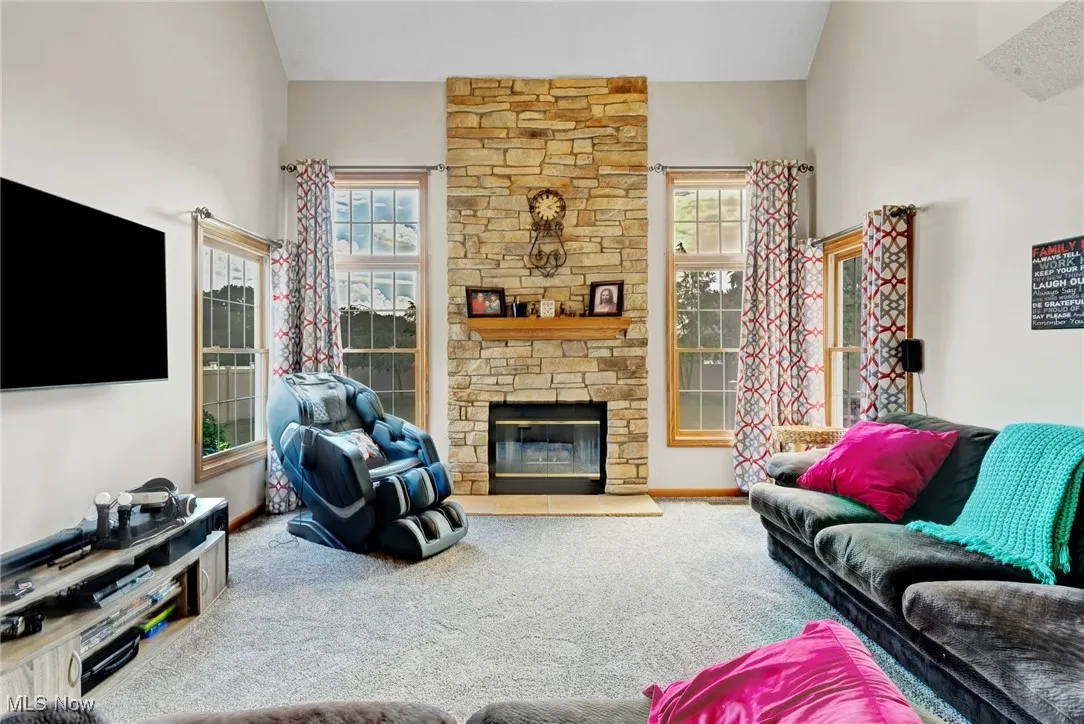 Living room with carpet floors and a stone fireplace