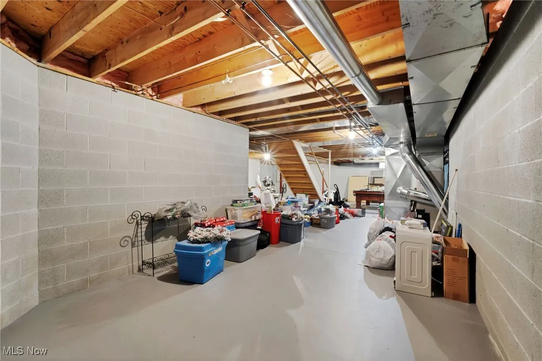 Unfinished below grade area featuring stairs and concrete block wall
