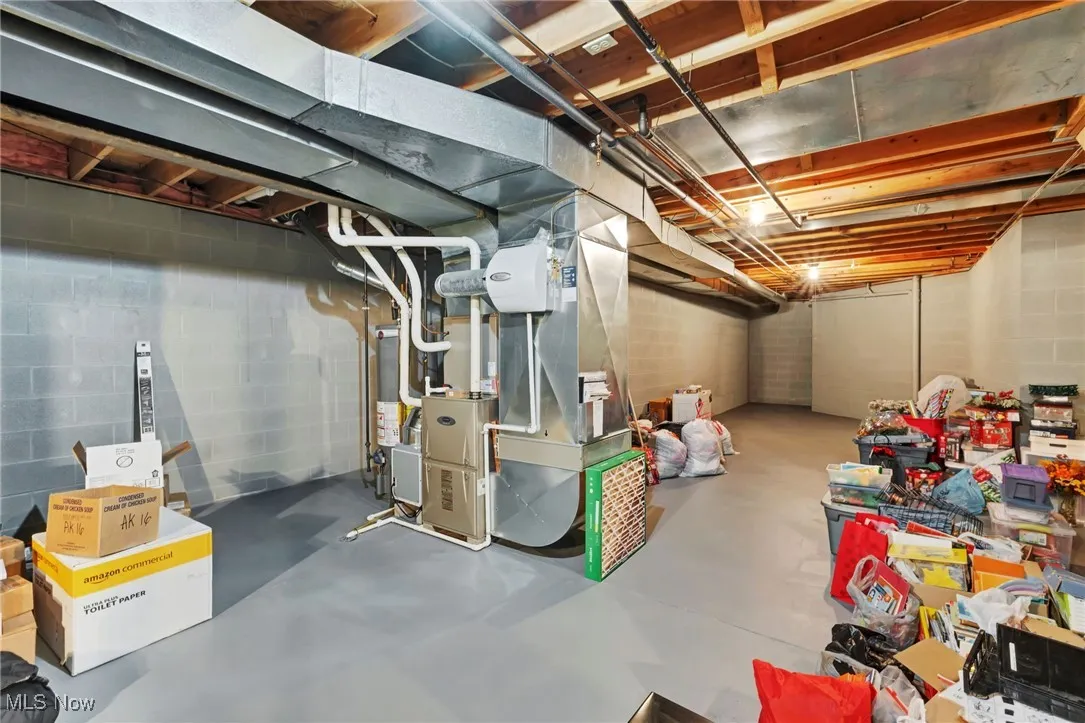 Unfinished basement with heating unit, concrete block wall, and gas water heater