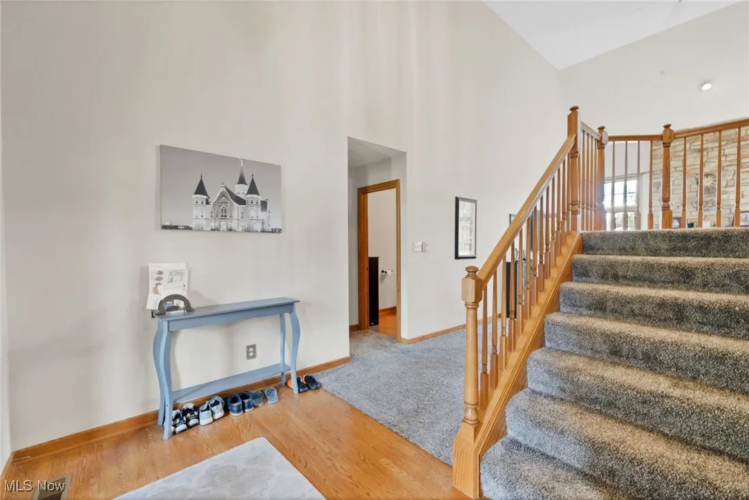 Stairway featuring wood finished floors and a towering ceiling