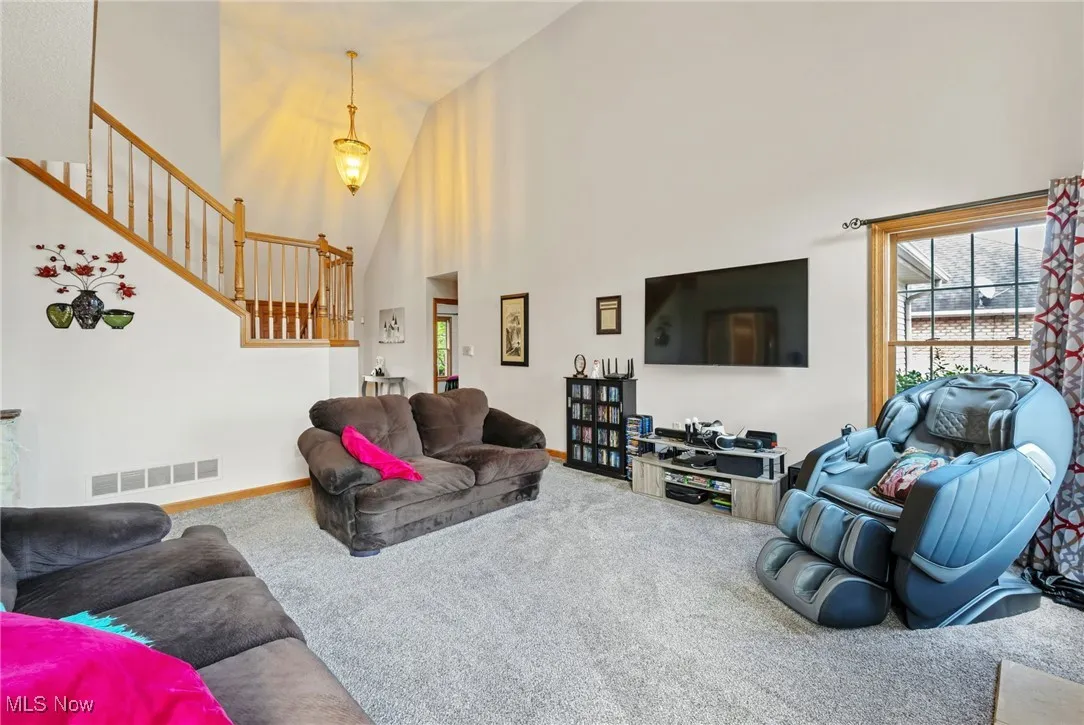 Carpeted living area featuring a towering ceiling and stairway