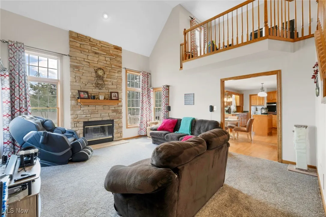 Carpeted living room with high vaulted ceiling, plenty of natural light, and a​​‌​​​​‌​​‌‌​‌‌​​​‌‌​‌​‌​‌​​​‌​​ fireplace