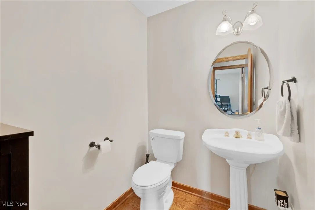 Half bathroom featuring toilet and wood finished floors