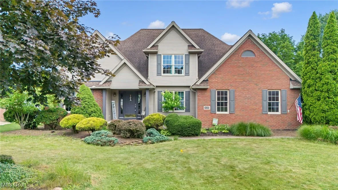 View of front of house featuring brick siding, a front lawn, and a shingled roof