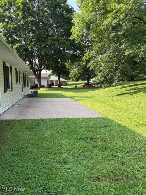 View of grassy yard with a patio area