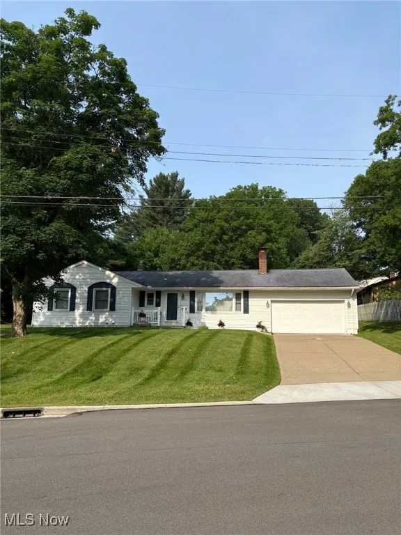 Single story home featuring a garage, driveway, a front yard, and a chimney