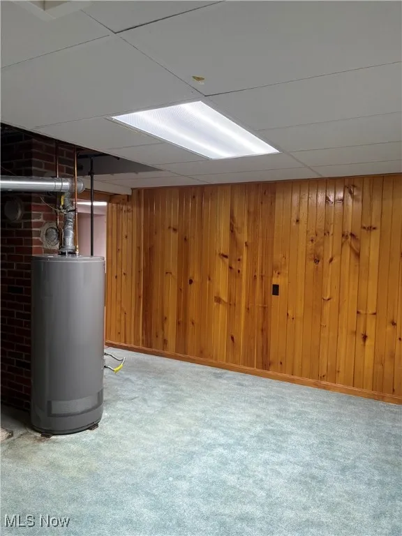Finished basement with water heater, carpet, and wooden walls