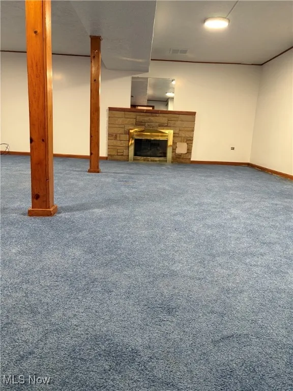 Unfurnished living room featuring carpet floors and a stone fireplace