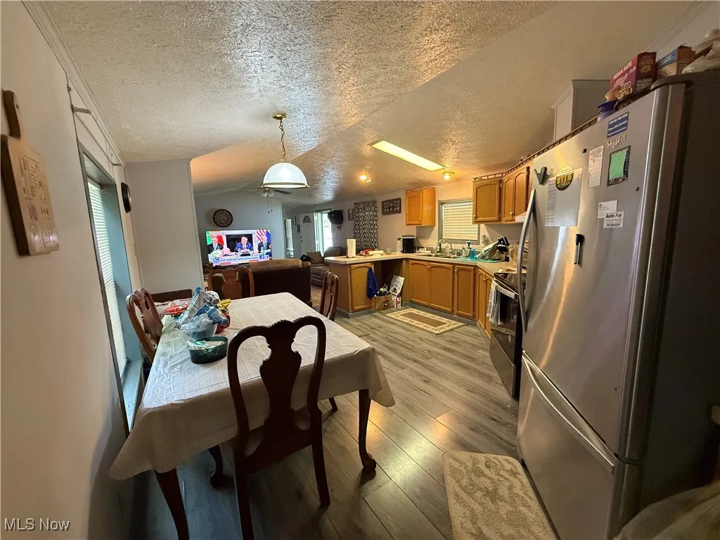 Dining space featuring a textured ceiling, light wood-type flooring, healthy amount of natural light, and ceiling fan