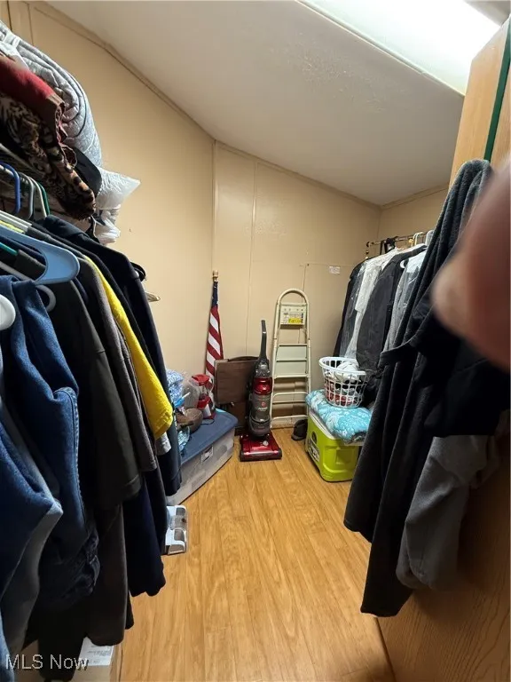 Spacious closet featuring wood finished floors and vaulted ceiling