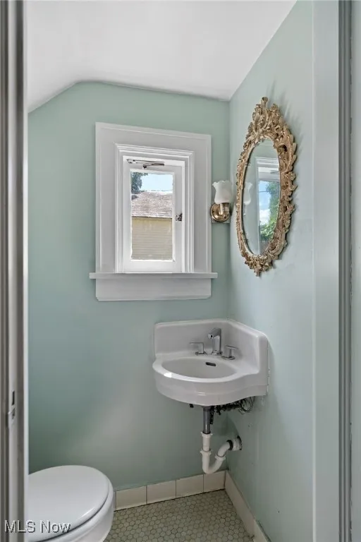 Half bathroom with vaulted ceiling and tile patterned flooring