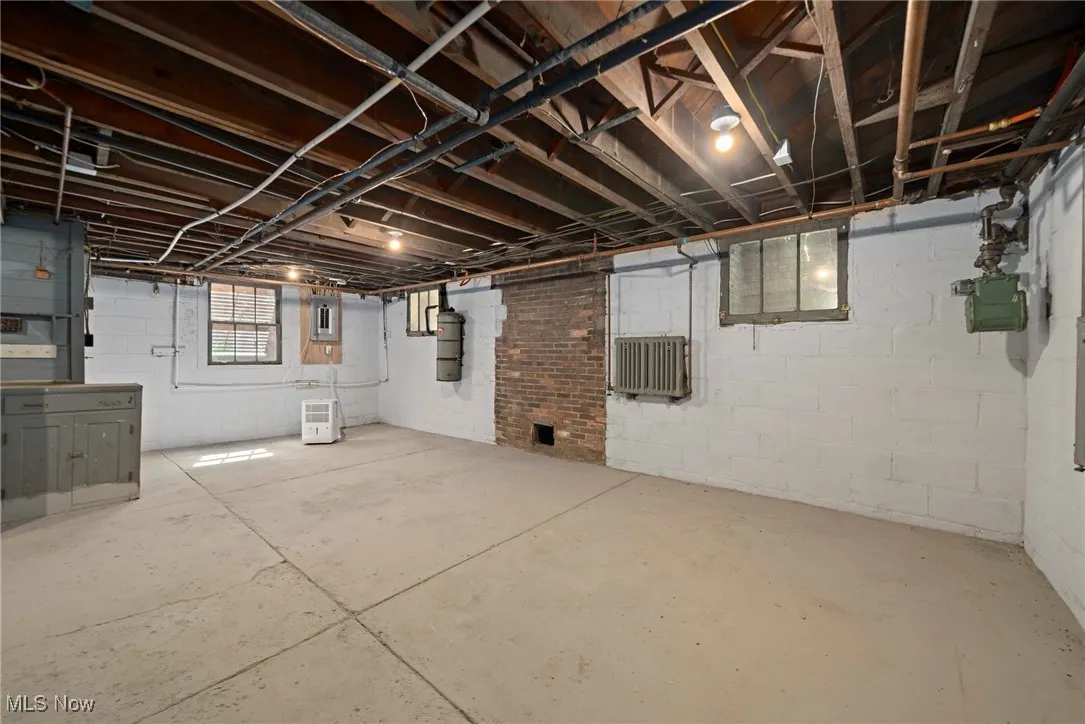Basement with electric panel and radiator heating unit