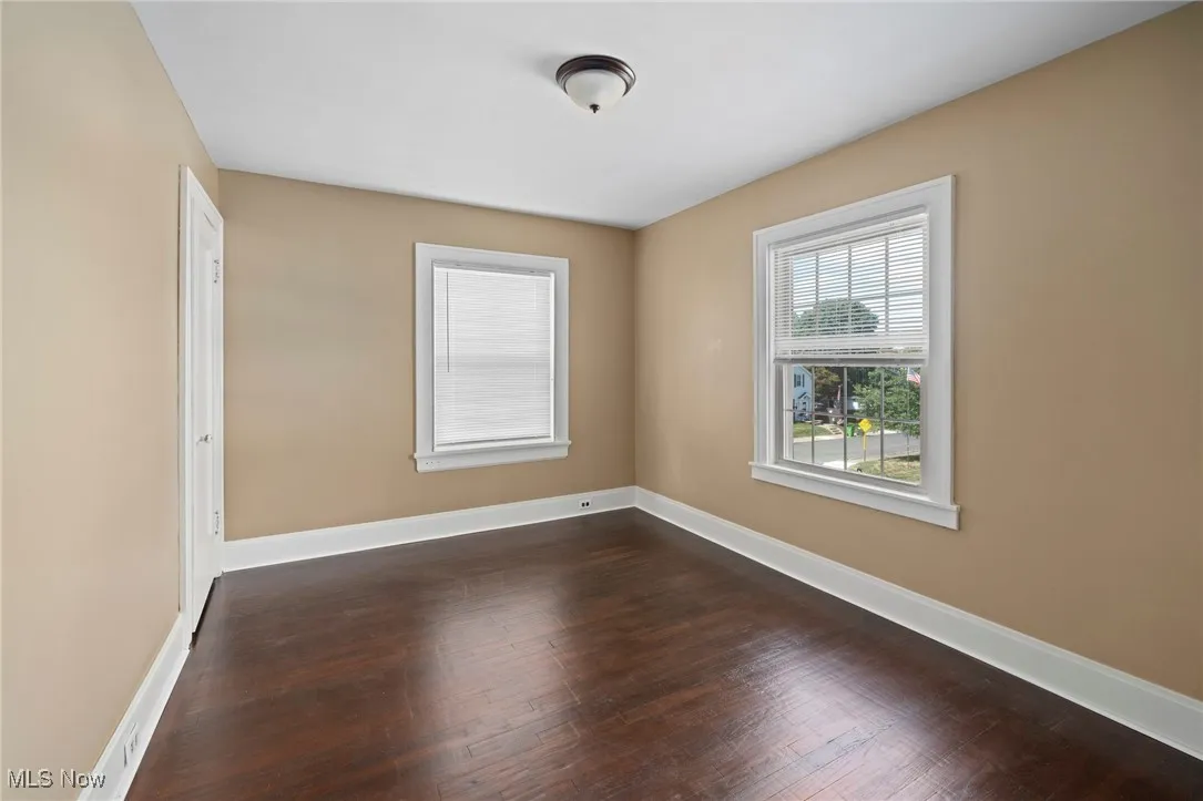 Unfurnished room featuring dark wood-style flooring and baseboards