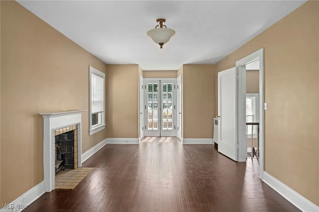 Unfurnished living room featuring dark wood-style floors and a fireplace with flush hearth