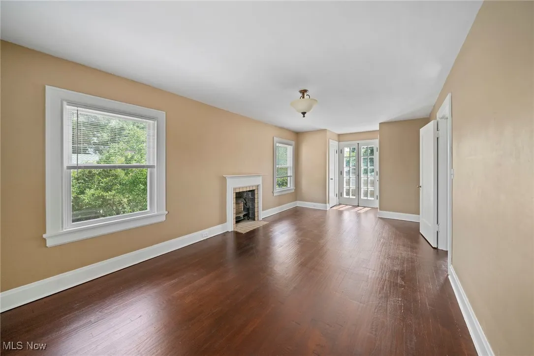 Unfurnished living room featuring dark wood-style flooring and a fireplace