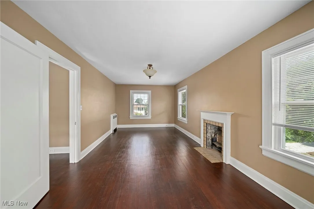Unfurnished living room with wood finished floors and radiator