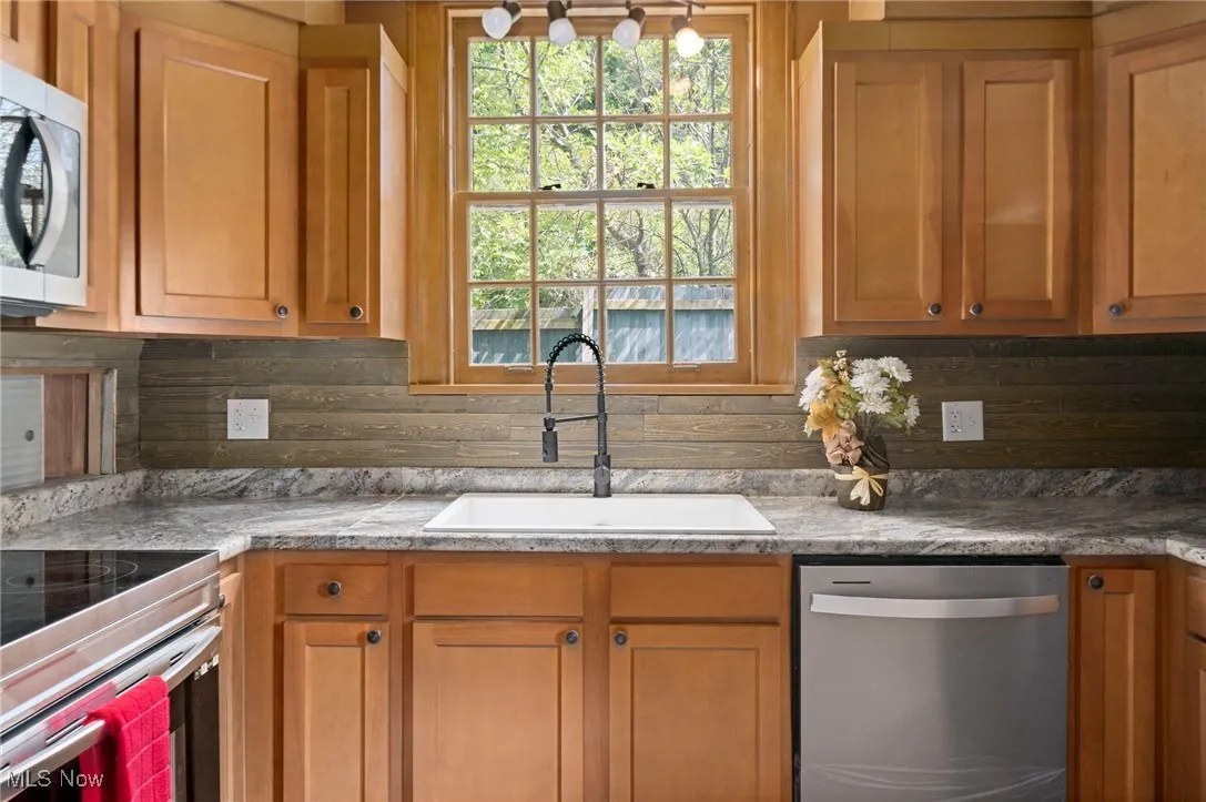 Kitchen with appliances with stainless steel finishes and decorative backsplash